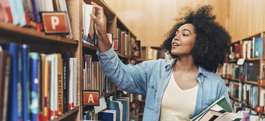 a woman looks at books on library shelves